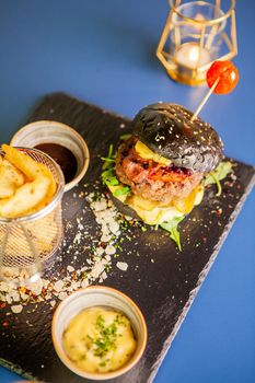 Jucy burger with french fries and soia sos on restaurant table. Tasty food