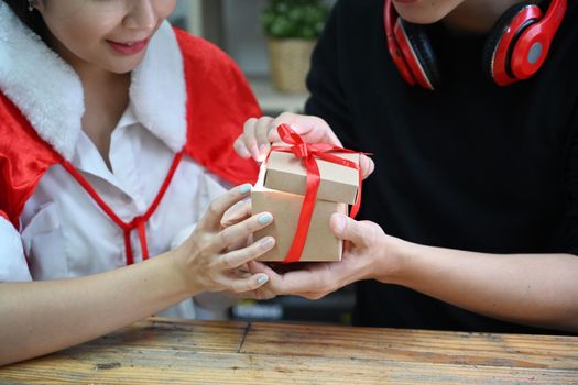Happy asian couple holding opening Christmas gift box together.