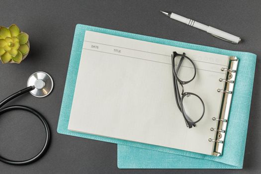 Open medical folder with glasses white pen stethoscope and houseplants on black background. Medical desk concept fight against respiratory disease coronavirus covid 19.
