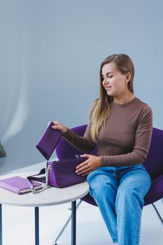 A purple leather bag in a girl's hand. Woman with luxury bag.