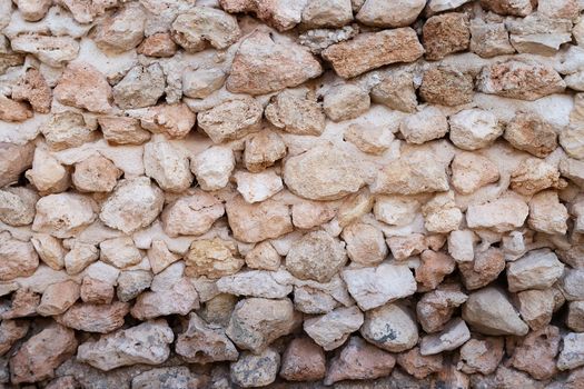 Stone background from small stones and bricks. Brickwork, wall of an old house. Summer day, sun rays. Copy-paste, for your product, design