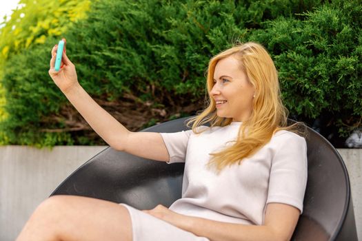 Young blond woman making selfie on smartphone for her followers. Young influencer girl. Popularity in internet, friends online. Beautiful girl making content for her social media account