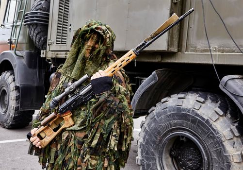 Close-up portrait of a military sniper in camouflage green army clothes with a Degtyarev sniper rifle in his hand. Armament of the Russian and Belarusian armies.