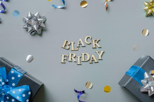 Black friday text with gifts and festive tinsel flat lay.