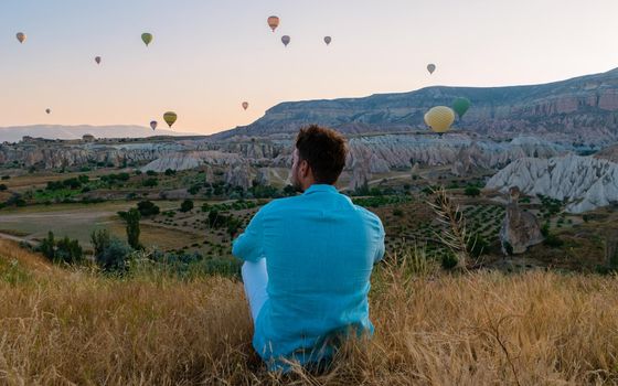 Young men watching hot air balloons during sunrise in Cappadocia Turkey, Kapadokya Goreme. Young caucasian men watching the sunrise in the valley of Cappadocia Turkey