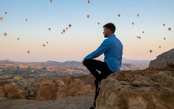 Young men watching hot air balloons during sunrise in Cappadocia Turkey, Kapadokya Goreme. Young caucasian men watching the sunrise in the valley of Cappadocia Turkey