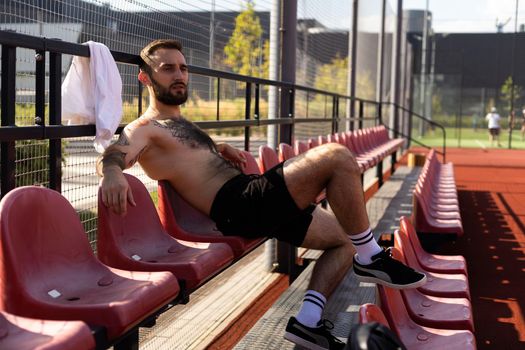 Young tired man resting, sitting after training.