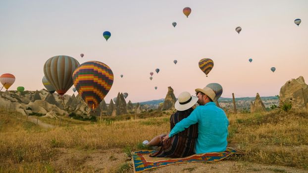 Asian women and caucasian men mid age on a trip to Kapadokya Cappadocia Turkey, a happy young couple during sunrise watching the hot air balloons of Kapadokya Cappadocia Turkey during vacation