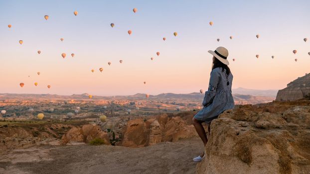 Asian women watching the sunset in Cappadocia with hot air balloons in the sky during sunrise in Cappadocia Turkey. Kapadokya Gorem. Happy mid age women in a hot air balloon