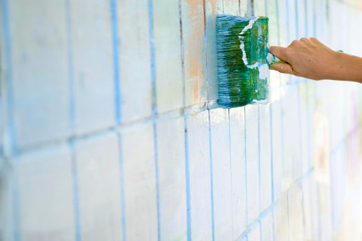 the process or skill of applying a substance to something so as to change its original color. Painting a tiled wall. Green and blue paint brush on white wall