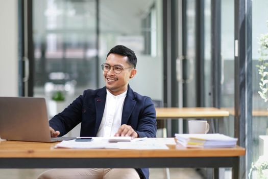 Successful and professional adult Asian businessman or male boss in formal suit working at his office desk..