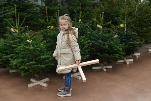 Small girl chooses a Christmas tree in the shop.
