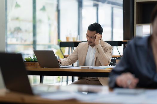 Stressed Asian businesswoman analyzes financial charts. Account and audit concept.