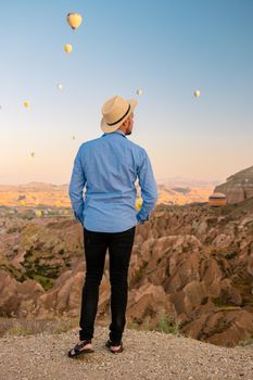 Young men watching hot air balloons during sunrise in Cappadocia Turkey, Kapadokya Goreme. Young caucasian men watching the sunrise in the valley of Cappadocia Turkey