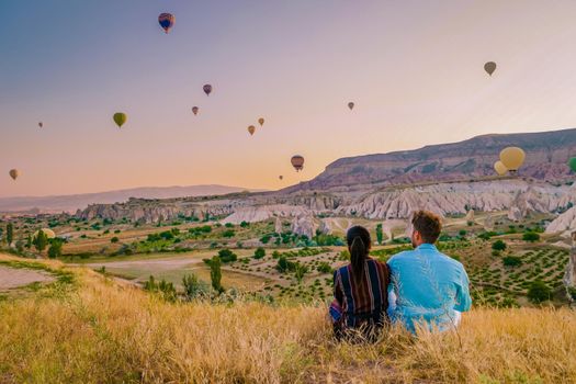 Asian women and caucasian men mid age on a trip to Kapadokya Cappadocia Turkey, a happy young couple during sunrise watching the hot air balloons of Kapadokya Cappadocia Turkey during vacation