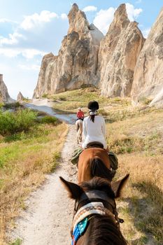 young woman during a vacation in Turkey Kapadokya watching the hot air balloons of Cappadocia. Asian women on the back of a brown horse in the valley of Cappadocia