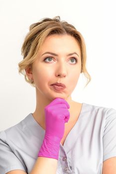 Young caucasian female doctor wearing gloves thoughtful looking away against a white background