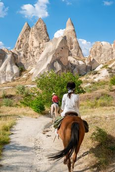 young woman during a vacation in Turkey Kapadokya watching the hot air balloons of Cappadocia. Asian women on the back of a brown horse in the valley of Cappadocia