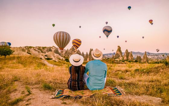 Kapadokya Cappadocia Turkey, a happy young couple during sunrise watching the hot air balloons of Kapadokya Cappadocia Turkey during vacation