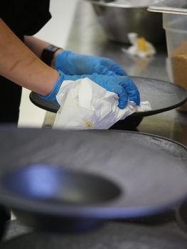 closeup of a chef hand wearing gloves serving and decorating a plate of pasta