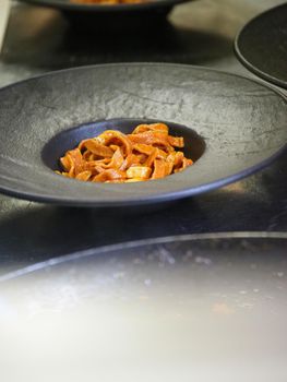 closeup of a chef hand wearing gloves serving and decorating a plate of pasta