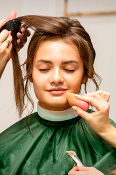 Makeup artist and hairdresser prepare the bride making hairstyle and makeup in a beauty salon