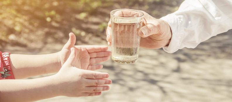 Grandmother giving a glass of clean water to a child. Selective focus.