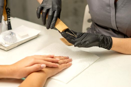 Manicure master takes out manicure tools from a kraft envelope in a nail salon