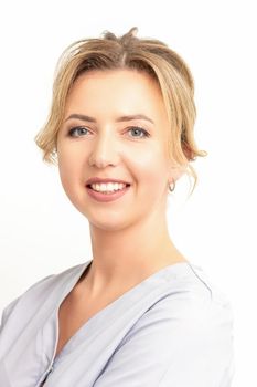 Close-up portrait of young smiling female caucasian healthcare worker standing staring at the camera on white background