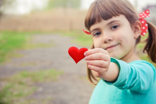 The heart is in the hands of the child. Selective focus.