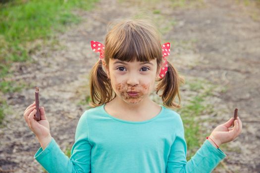 A sweet-toothed child eats chocolate. Selective focus.