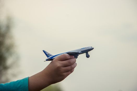 The plane is in the hands of the child. Selective focus.