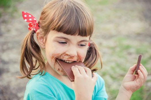 A sweet-toothed child eats chocolate. Selective focus.