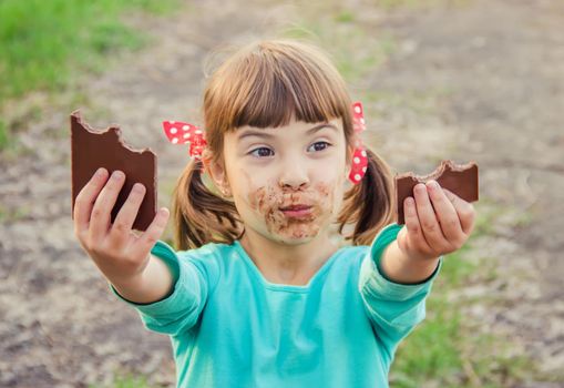 A sweet-toothed child eats chocolate. Selective focus.