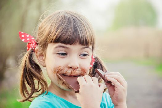 A sweet-toothed child eats chocolate. Selective focus.