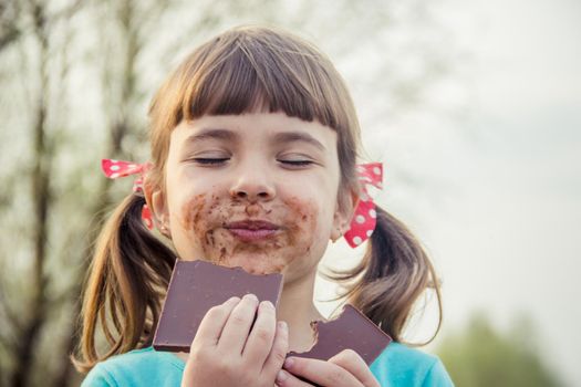 A sweet-toothed child eats chocolate. Selective focus.