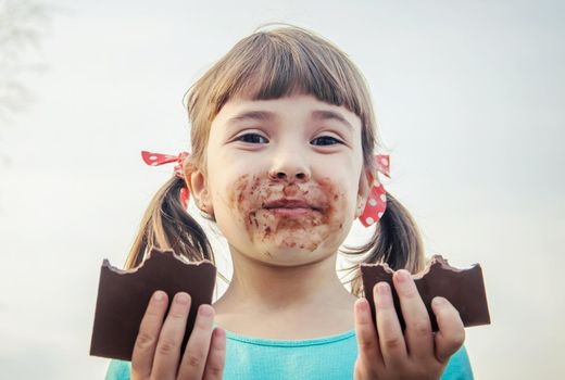 A sweet-toothed child eats chocolate. Selective focus.