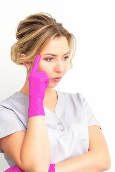 Young caucasian female doctor wearing gloves thoughtful looking away isolated on white background