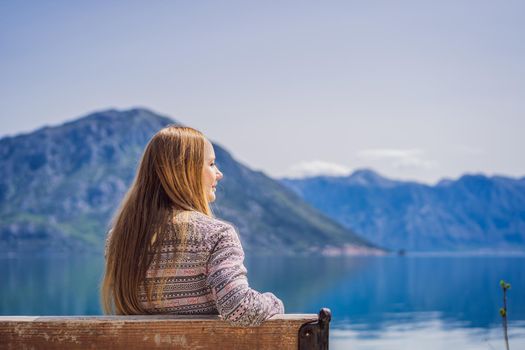 A woman sits on a bench and admires the view of the Bay of Kotor. Montenegro.