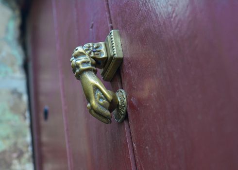 Vinous old door with doorknocker Metal arm of woman or man