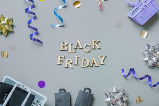 Black friday text with gifts, shopping baskets and festive tinsel flat lay.