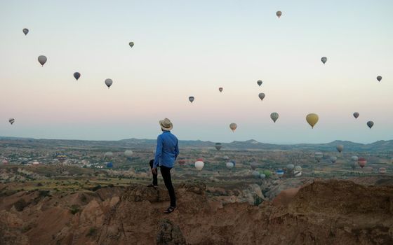 Young men watching hot air balloons during sunrise in Cappadocia Turkey, Kapadokya Goreme. Young caucasian men watching the sunrise in the valley of Cappadocia Turkey