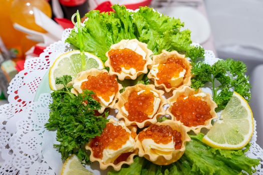 Red caviar and grated cheese in small dough baskets. A delicious cold appetizer with seafood. Close up.