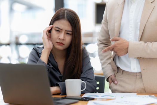 Stressed Asian businesswoman analyzes financial charts. Account and audit concept.