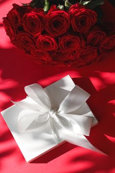 Happy holidays, luxe shopping and love gifts concept - Luxury holiday silk gift box and bouquet of roses on red background, romantic surprise and flowers as birthday or Valentines Day present