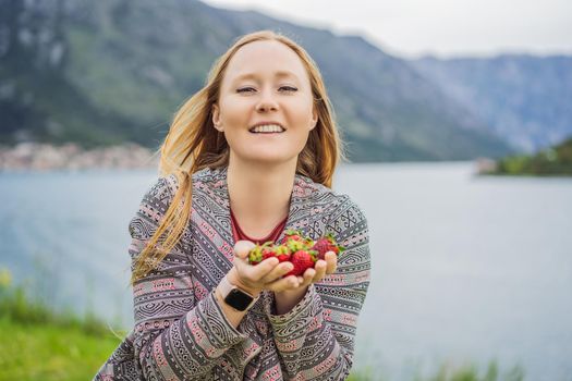 Young attractive woman eating a strawberry, outdoors.