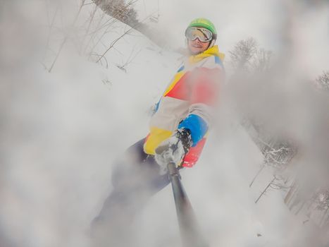 Skier skiing downhill during cloudy day in high mountains.