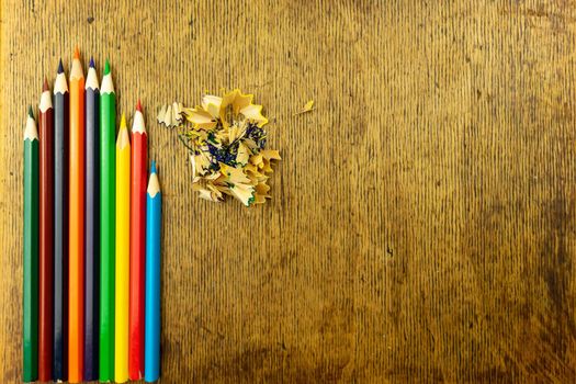 Several sharpened crank pencils on a vintage wooden surface.