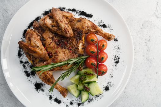 Grilled fried Chicken Tabaka and fresh vegetables on white plate