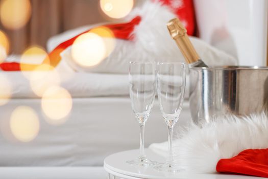 Two glasses and a bottle of champagne in a hotel room with Christmas decor. The concept of celebrating the new year in travel and hotel.